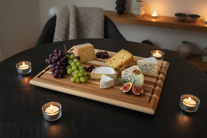 cutting bored on a round table with cheese and grapes on it